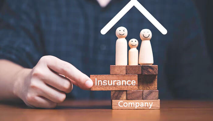 Visual concept showing wooden blocks labeled “Insurance Company” with a family figurine under a roof—symbolizing protection and guidance on how to start an insurance company.