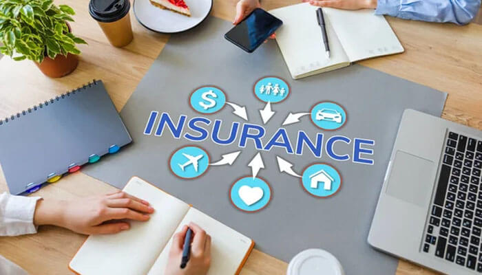 What Is An Insurance Underwriter – Insurance concept showing various types of insurance coverage like health, auto, home, and life with professionals discussing policies around a table.