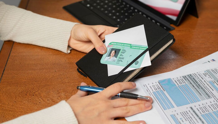 Person handling documents, identification card, and forms at a desk—representing administrative steps in how to start an insurance company.