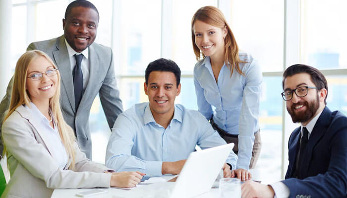 Group of professional employees smiling in a modern office setting, representing the positive work environment at the best insurance companies to work for.
