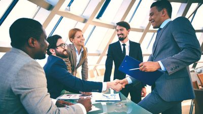 Business professionals shaking hands in a modern office — symbolizing partnership and success after completing the process to register a company in New Zealand.