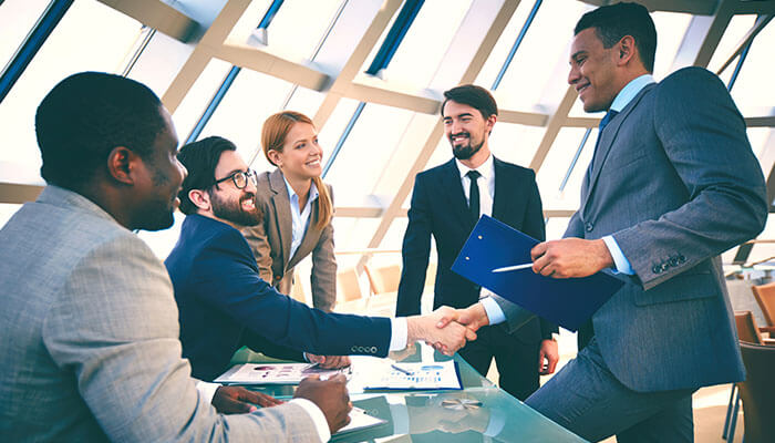 Business professionals shaking hands in a modern office — symbolizing partnership and success after completing the process to register a company in New Zealand.