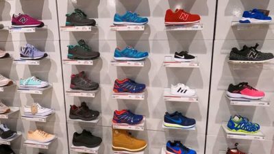 Display wall of branded sneakers in a retail store, representing sneaker reselling and online authentication platforms while addressing the question Is StockX Legit.